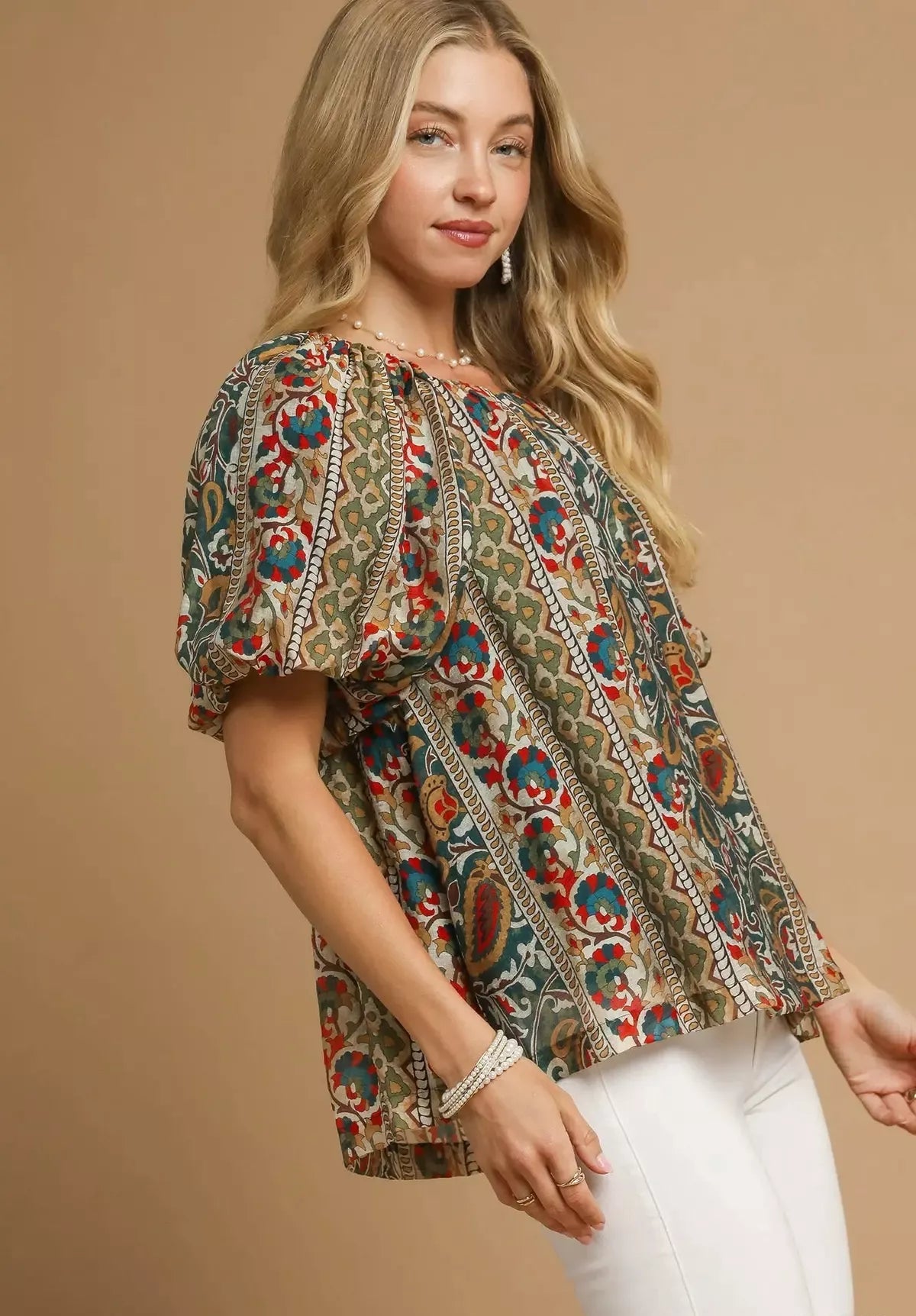 Woman wearing a patterned blouse with puff sleeves against a beige background