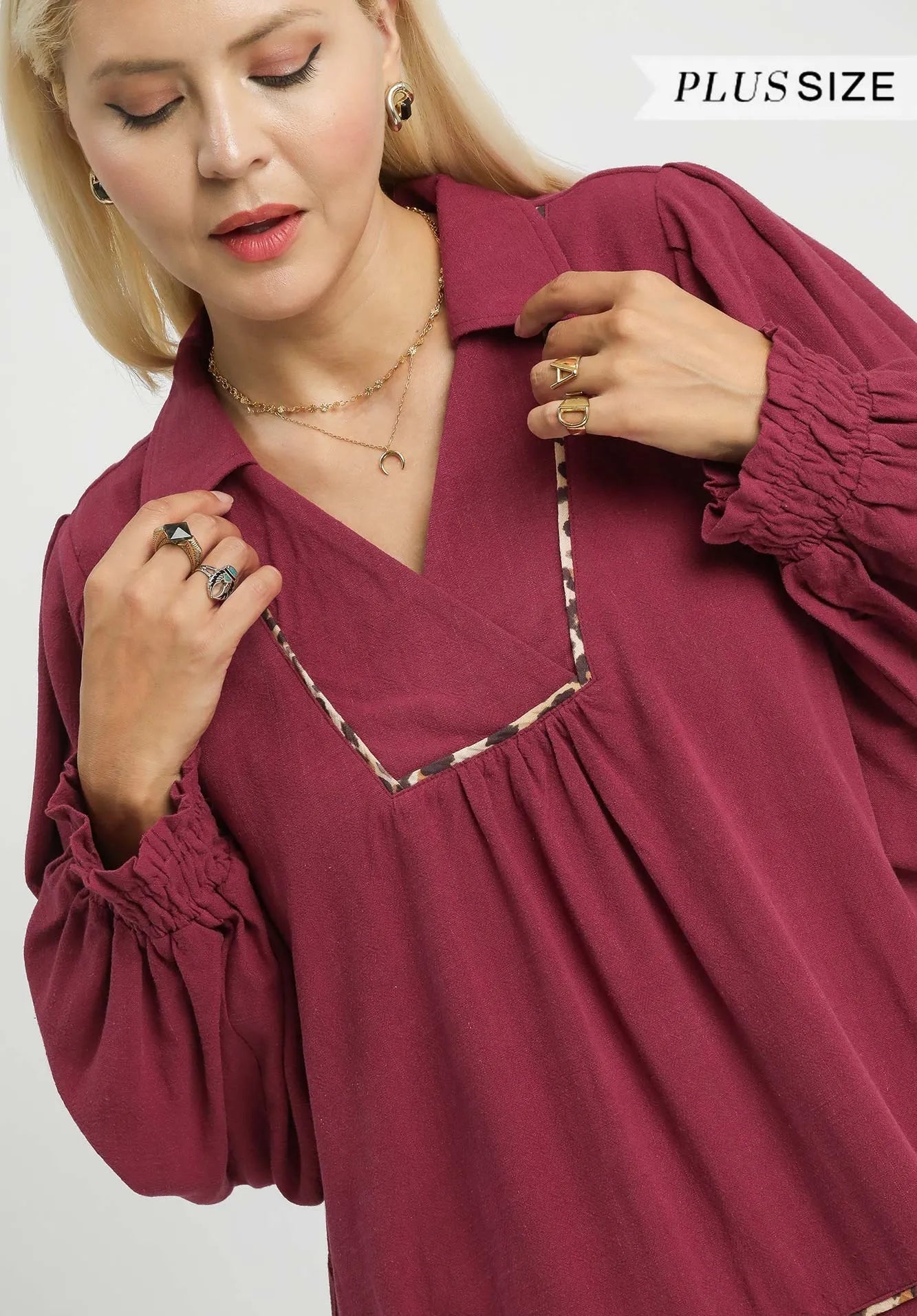 Woman wearing a burgundy plus-size blouse with long sleeves on a white background
