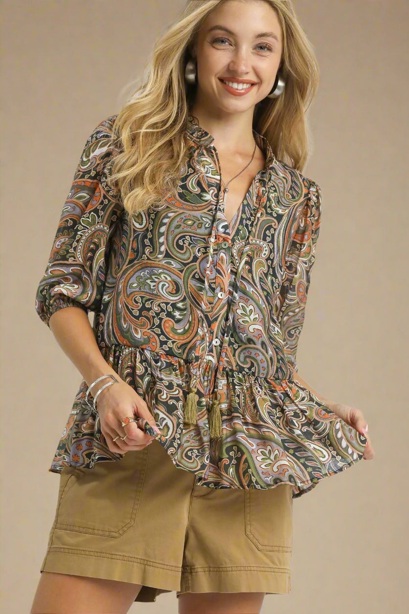Woman wearing a patterned blouse and beige shorts on a beige background