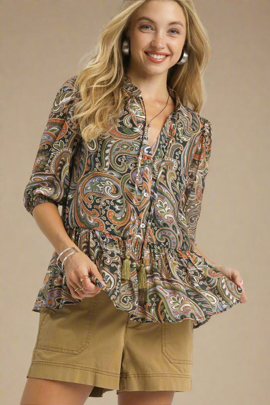 Woman wearing a patterned blouse and beige shorts on a beige background