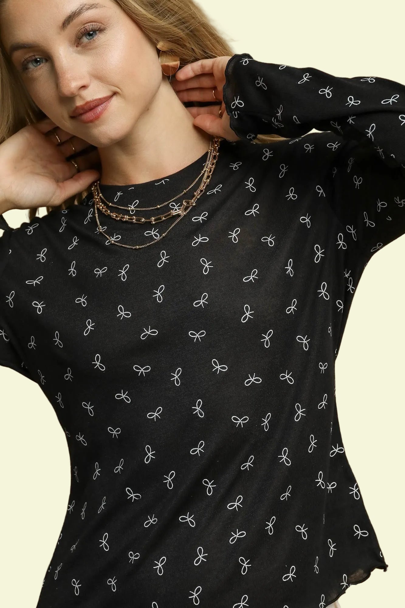 Woman wearing a black long-sleeve top with white patterns on a beige background