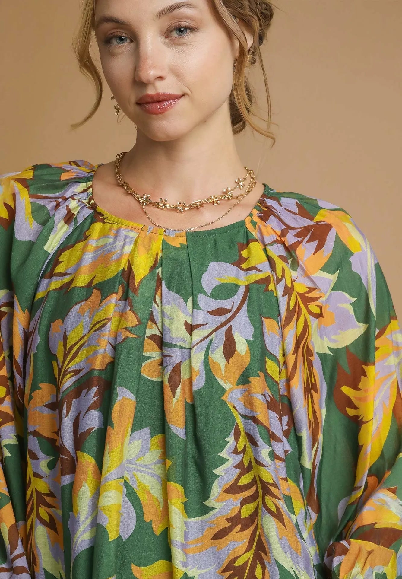 Woman wearing a colorful floral blouse with a neutral background