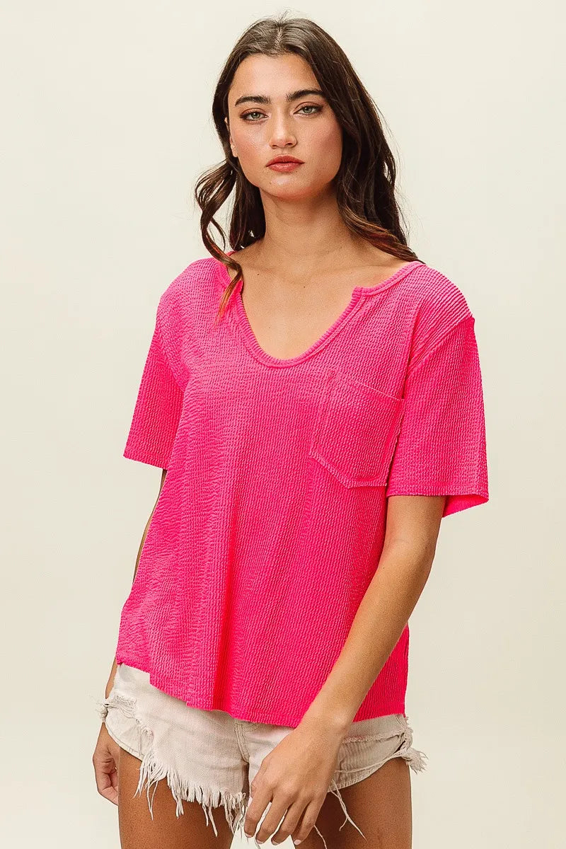 Woman wearing a bright pink textured top with a neutral background