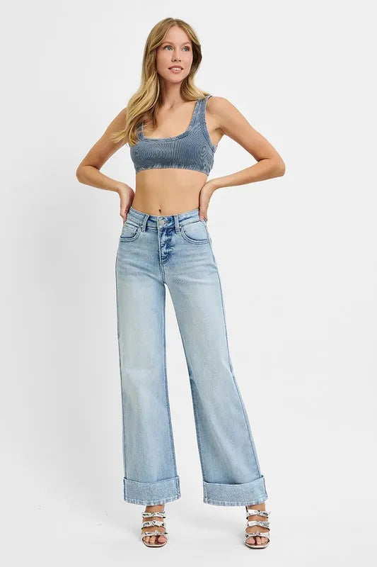 Woman wearing a blue crop top and light blue jeans on a white background