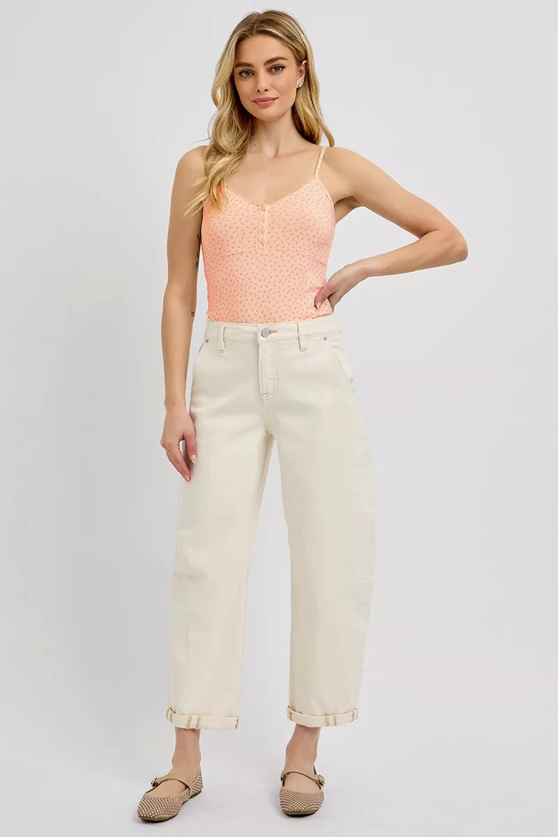 Woman wearing a pink sleeveless top and white pants on a plain background