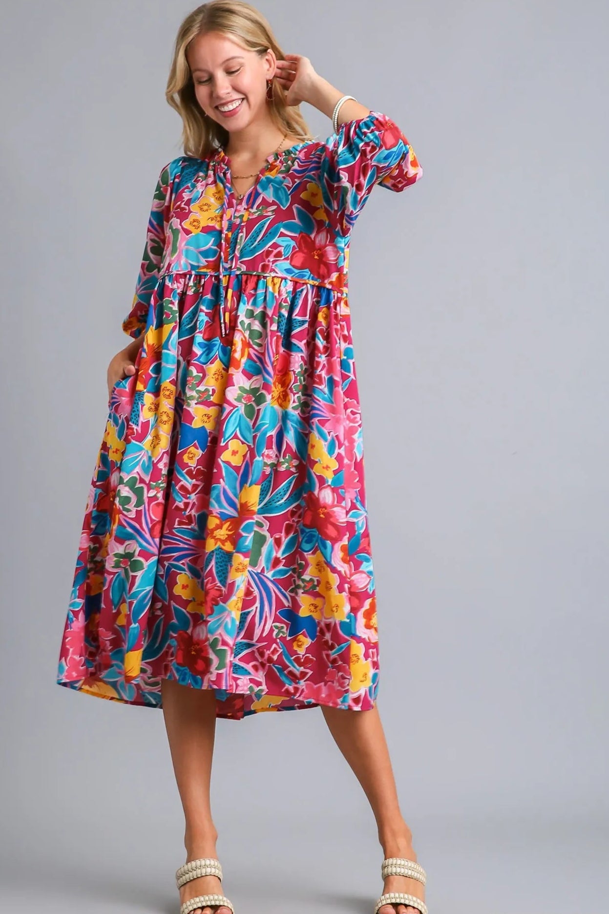 Woman wearing a colorful floral dress on a gray background