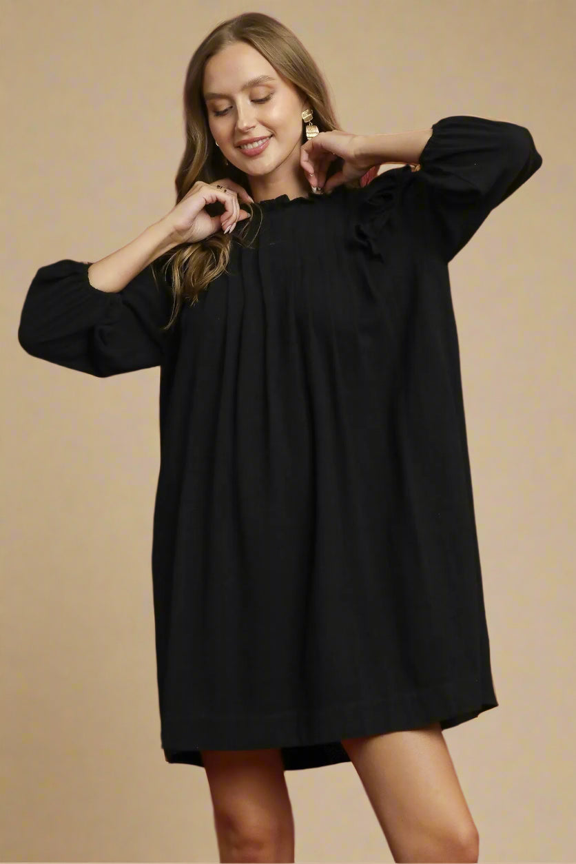 Woman wearing a black dress against a beige background