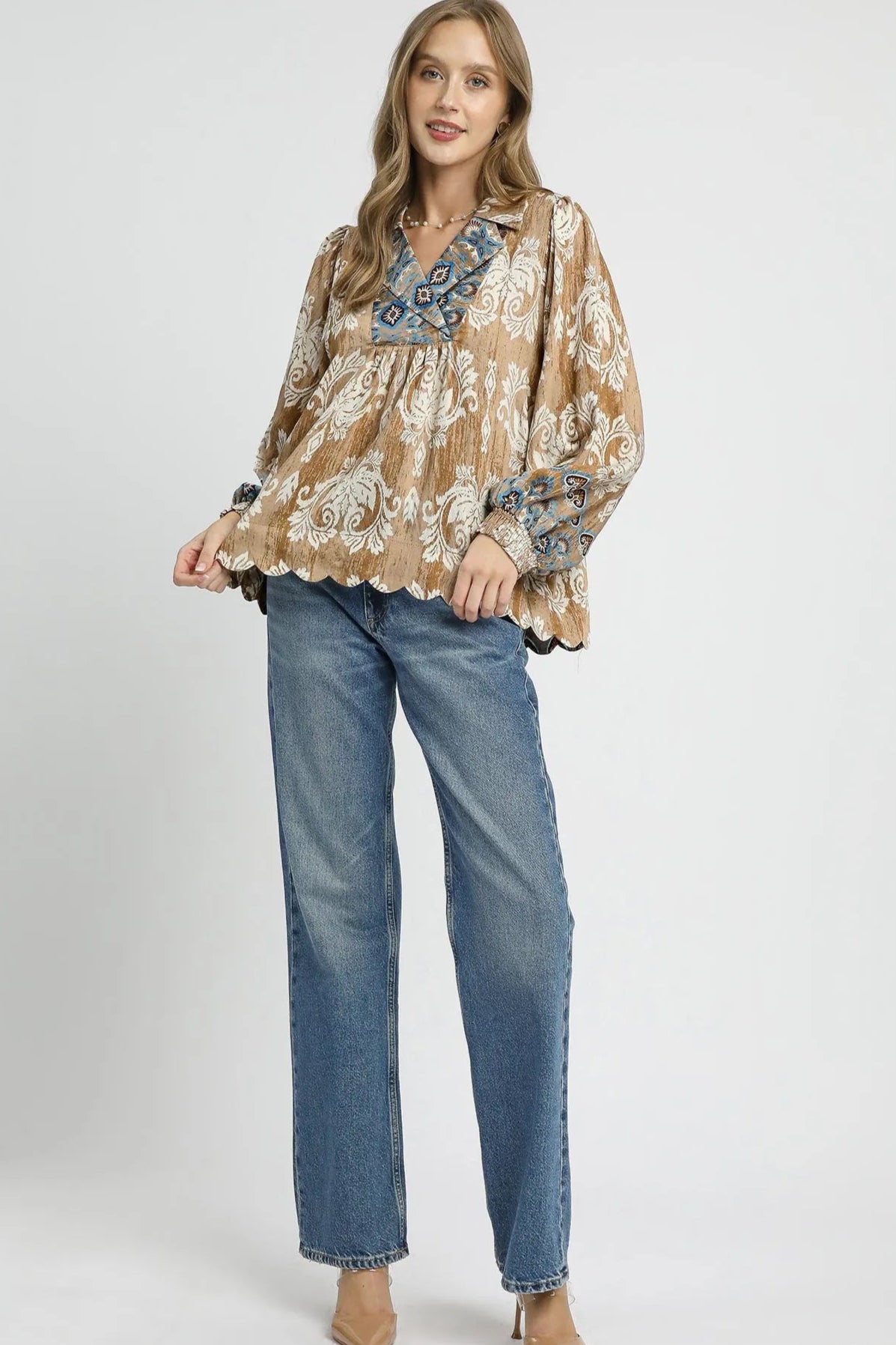 Woman wearing a patterned blouse and jeans on a white background