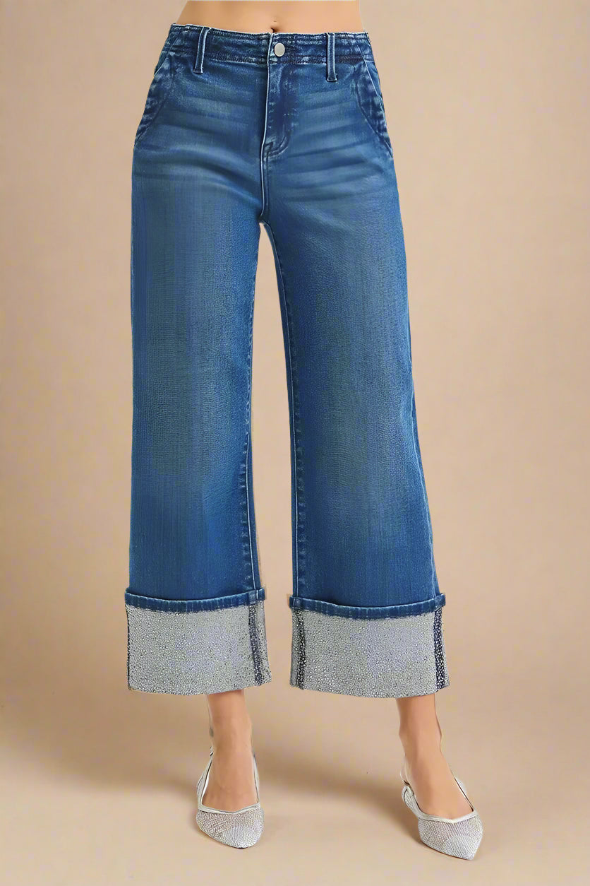 Blue jeans with cuffed hems on a beige background