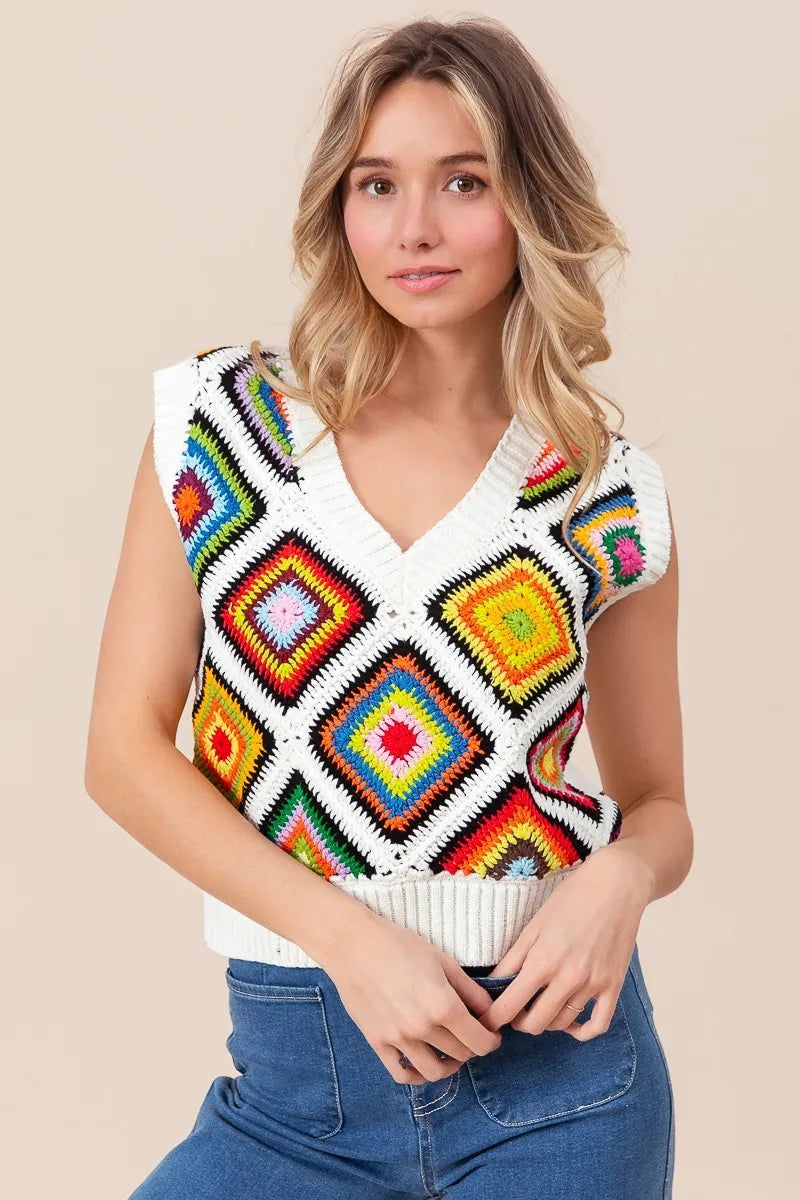 Woman wearing a colorful geometric-patterned sleeveless sweater against a beige background