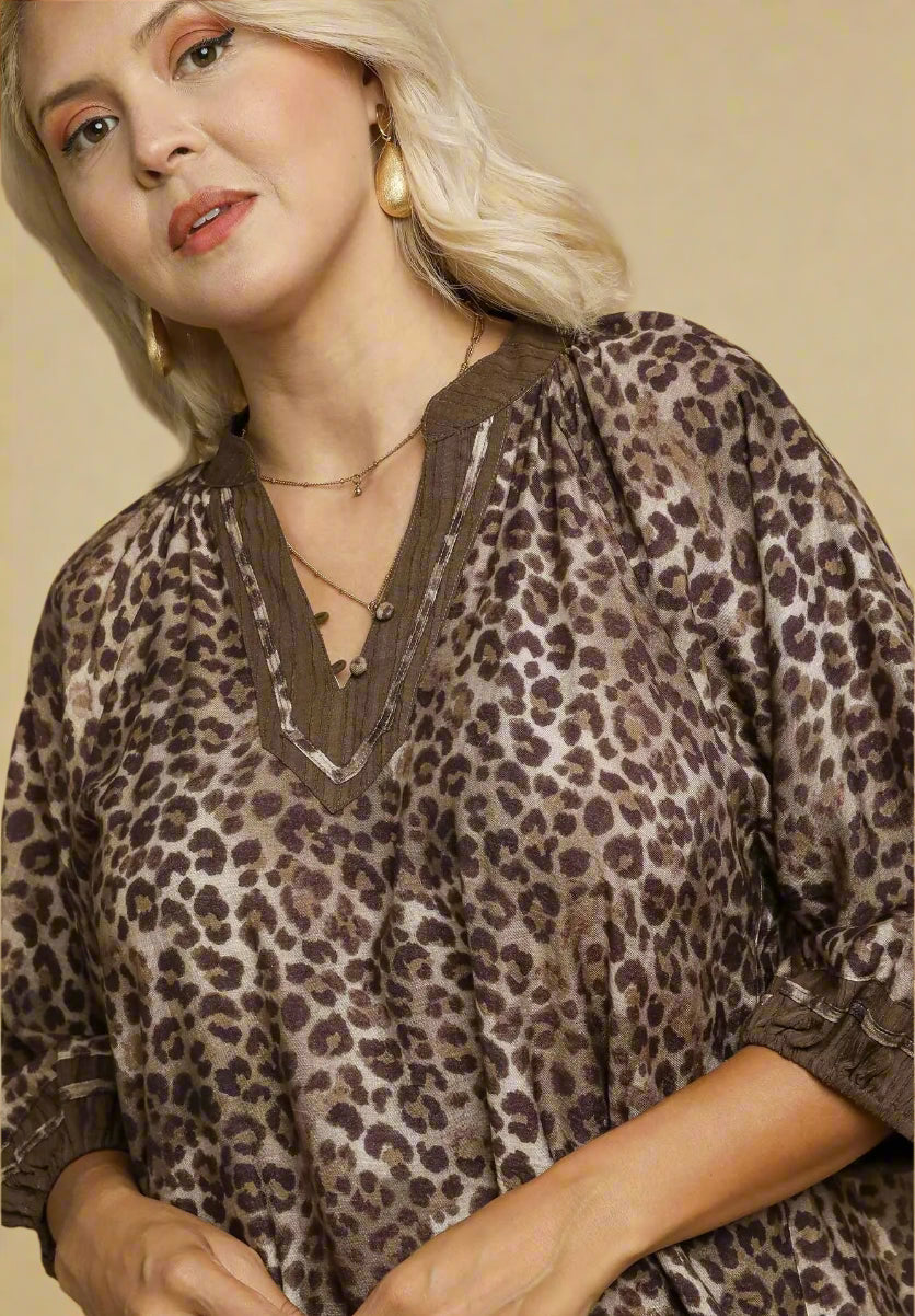 Woman wearing a leopard print dress with a brown trim on a beige background