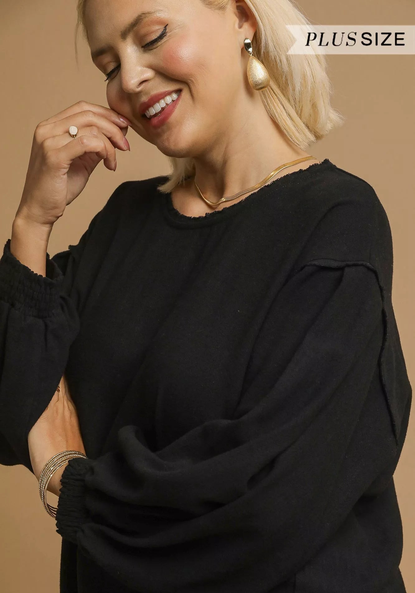 Woman wearing a black outfit with 'Plus Size' text on a beige background