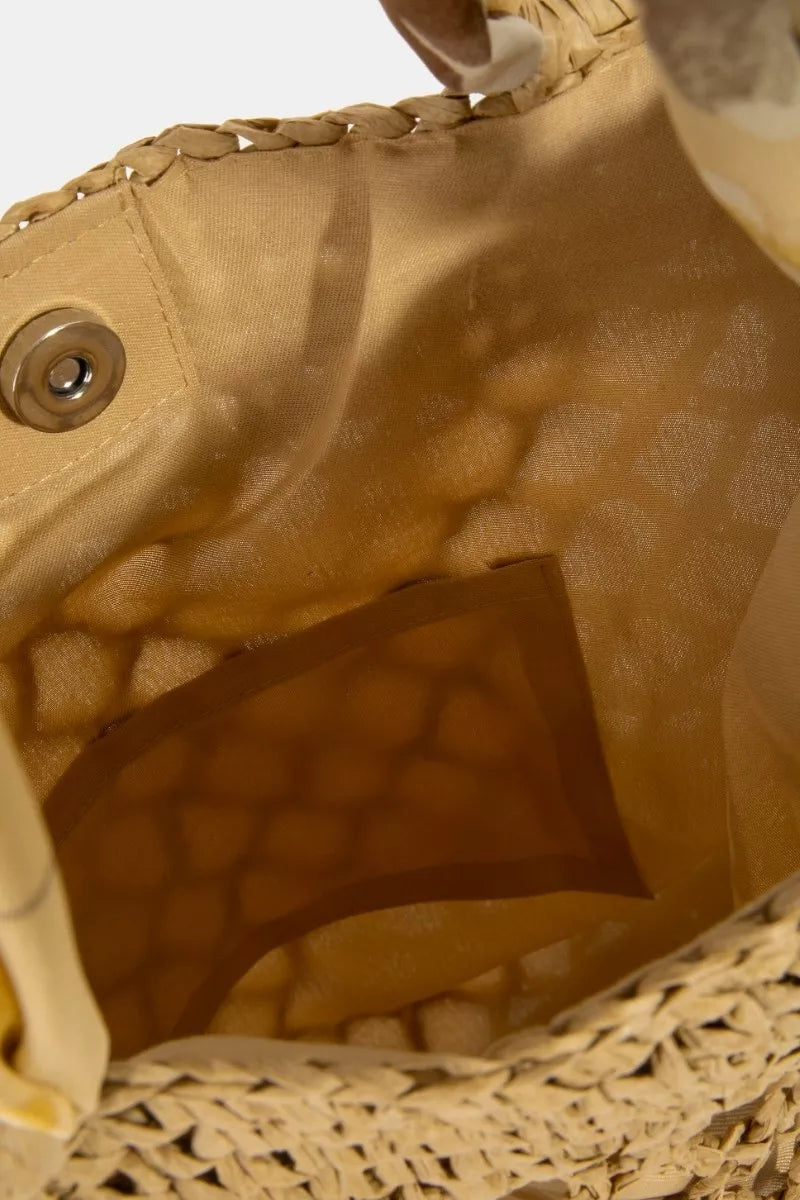 Close-up of a beige woven handbag with a brown interior pocket.