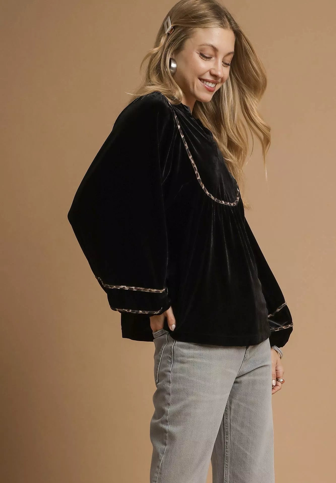 Woman wearing a black velvet top with chain details on a beige background