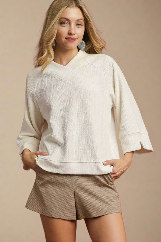 Woman wearing a white sweater and beige shorts against a red background