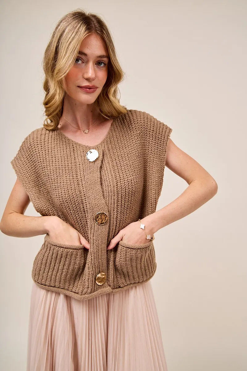 Woman wearing a brown knitted vest with a beige background