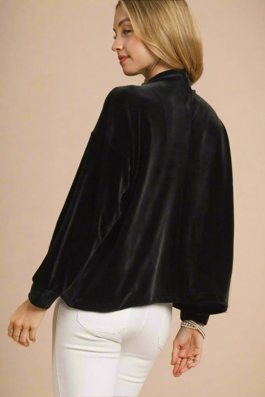 Woman wearing a black velvet jacket on a beige background