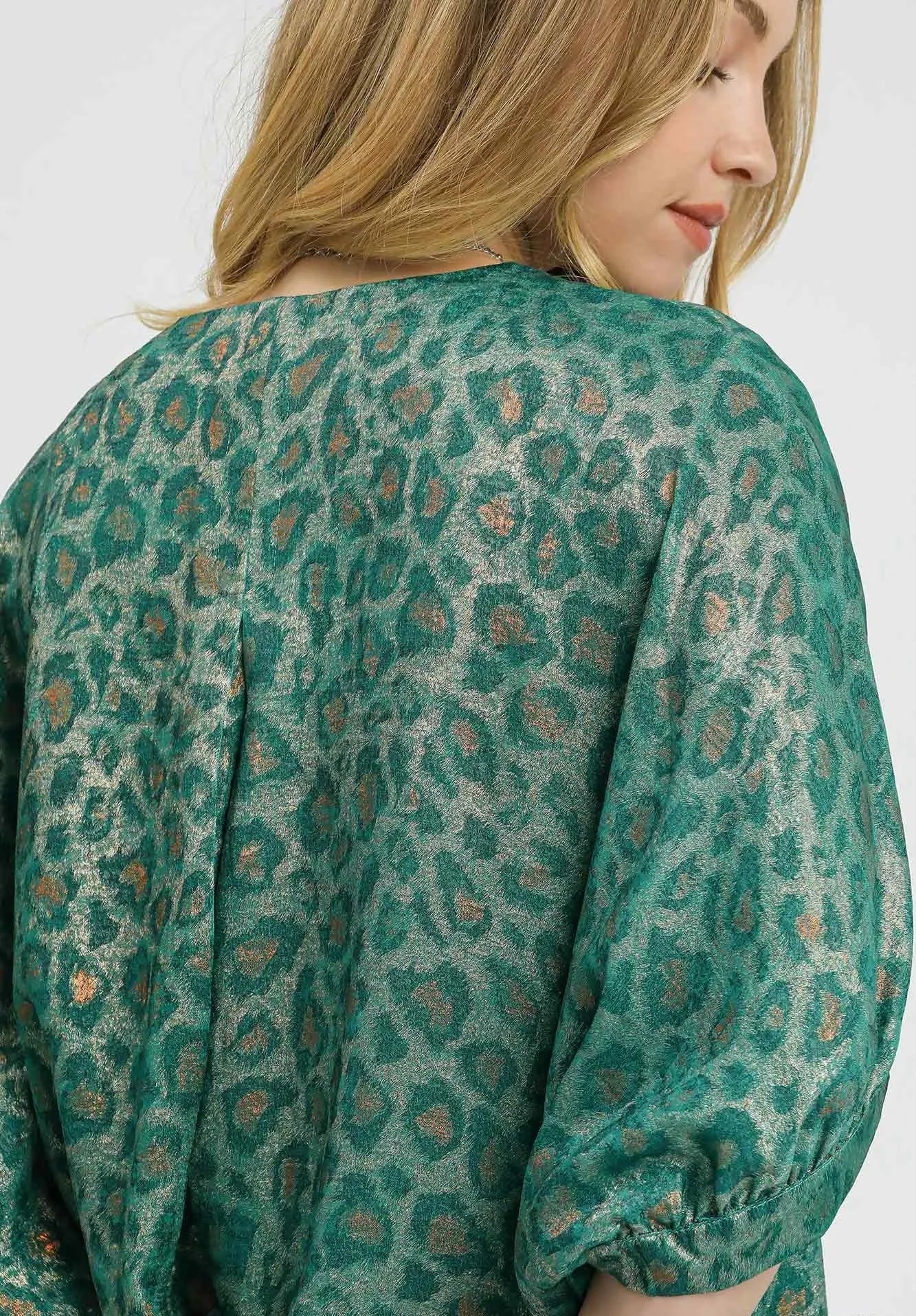 Woman wearing a green patterned blouse against a white background