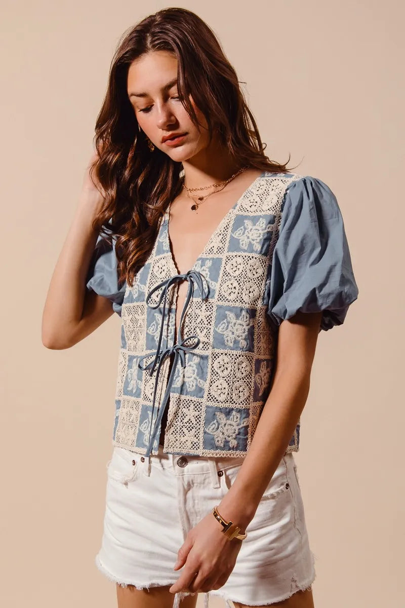 Woman wearing a patterned top with puff sleeves against a beige background