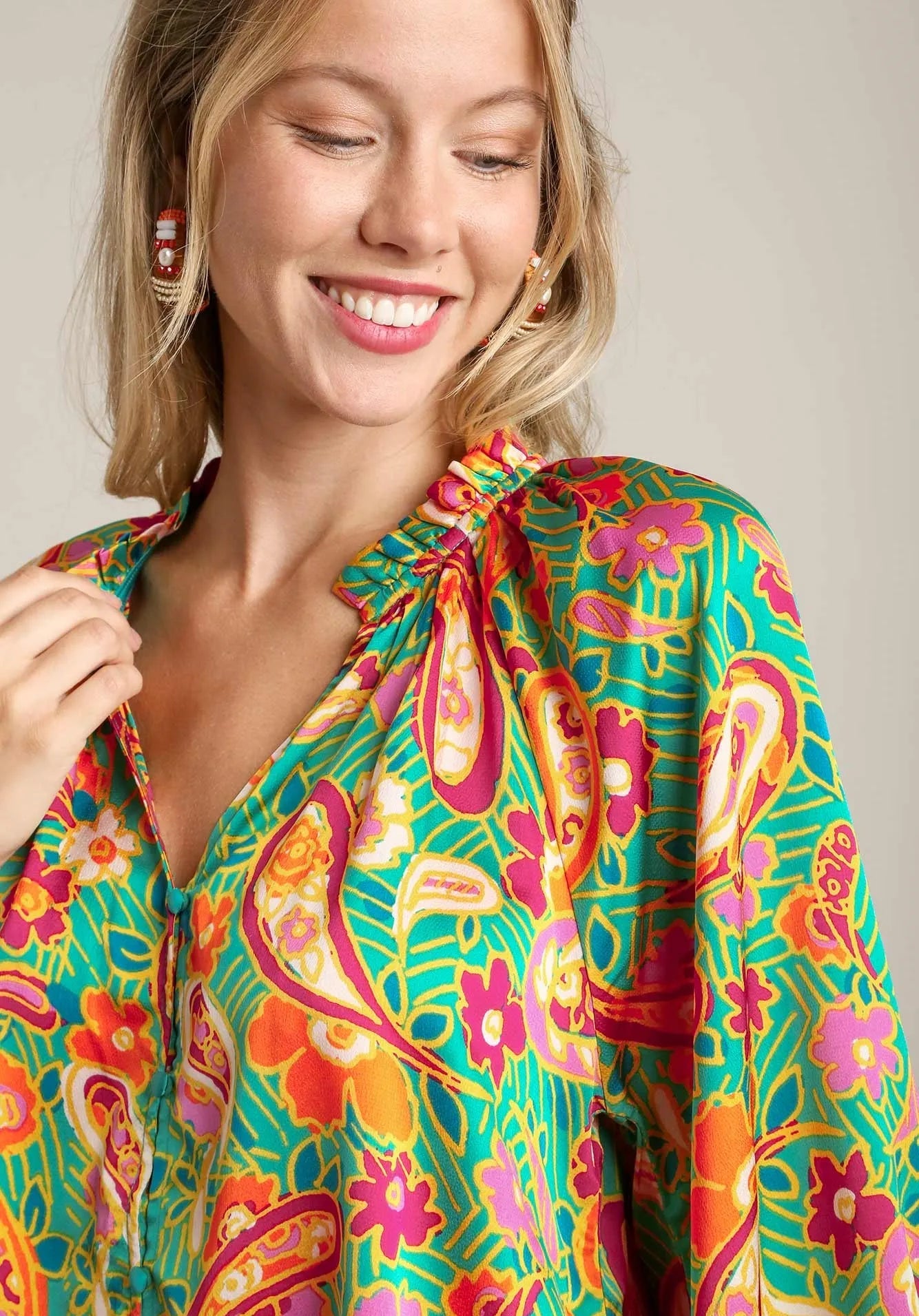 Woman wearing a colorful patterned top against a neutral background