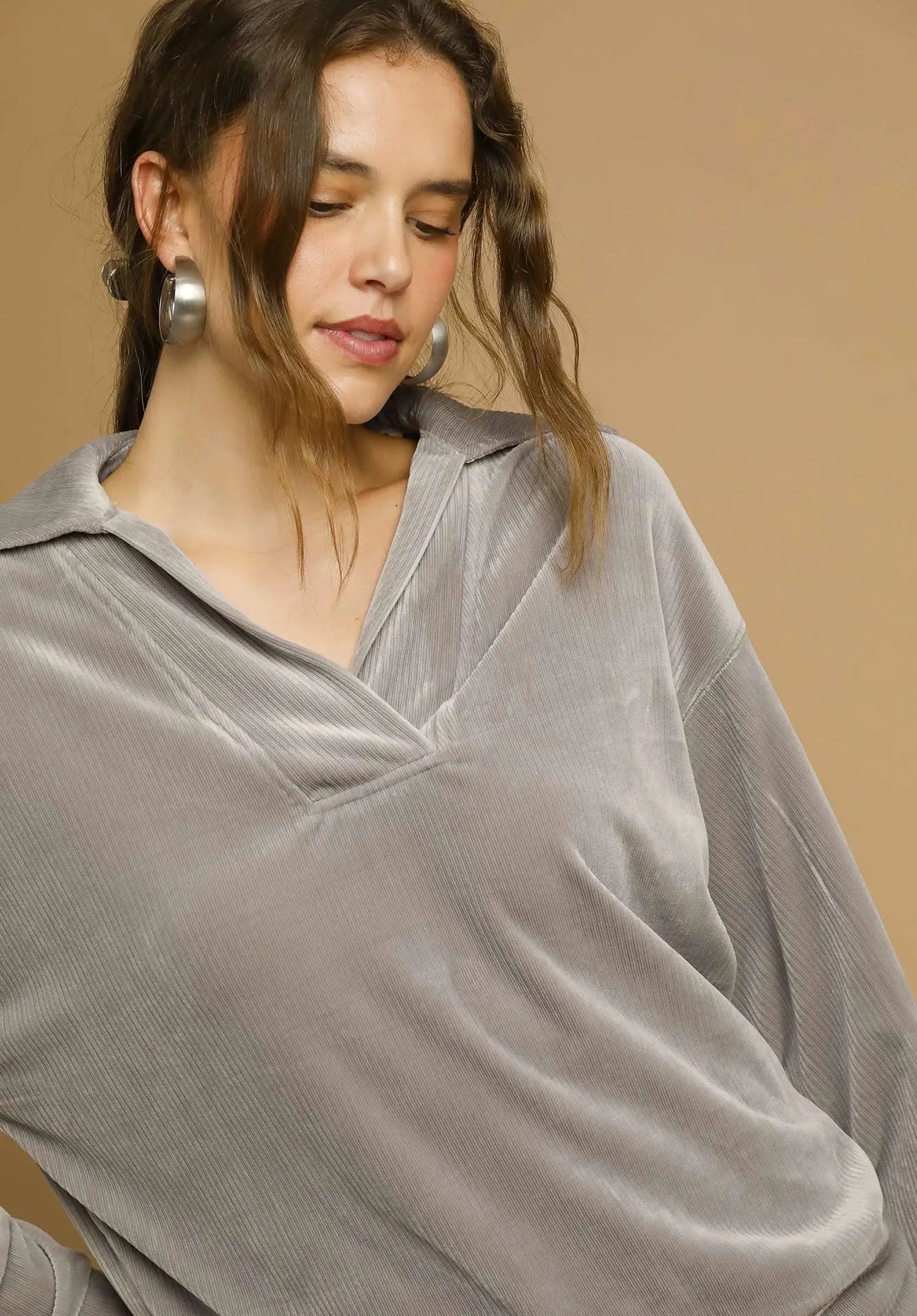 Woman wearing a gray velvet garment against a beige background