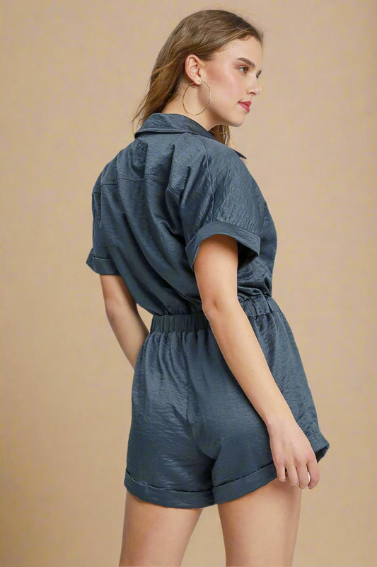 Woman wearing a navy blue romper on a light gray background