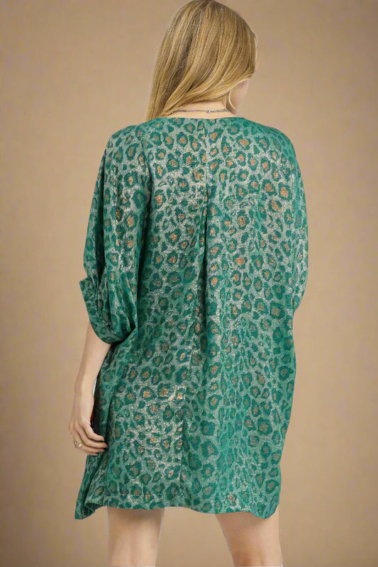 Woman wearing a teal patterned dress on a white background