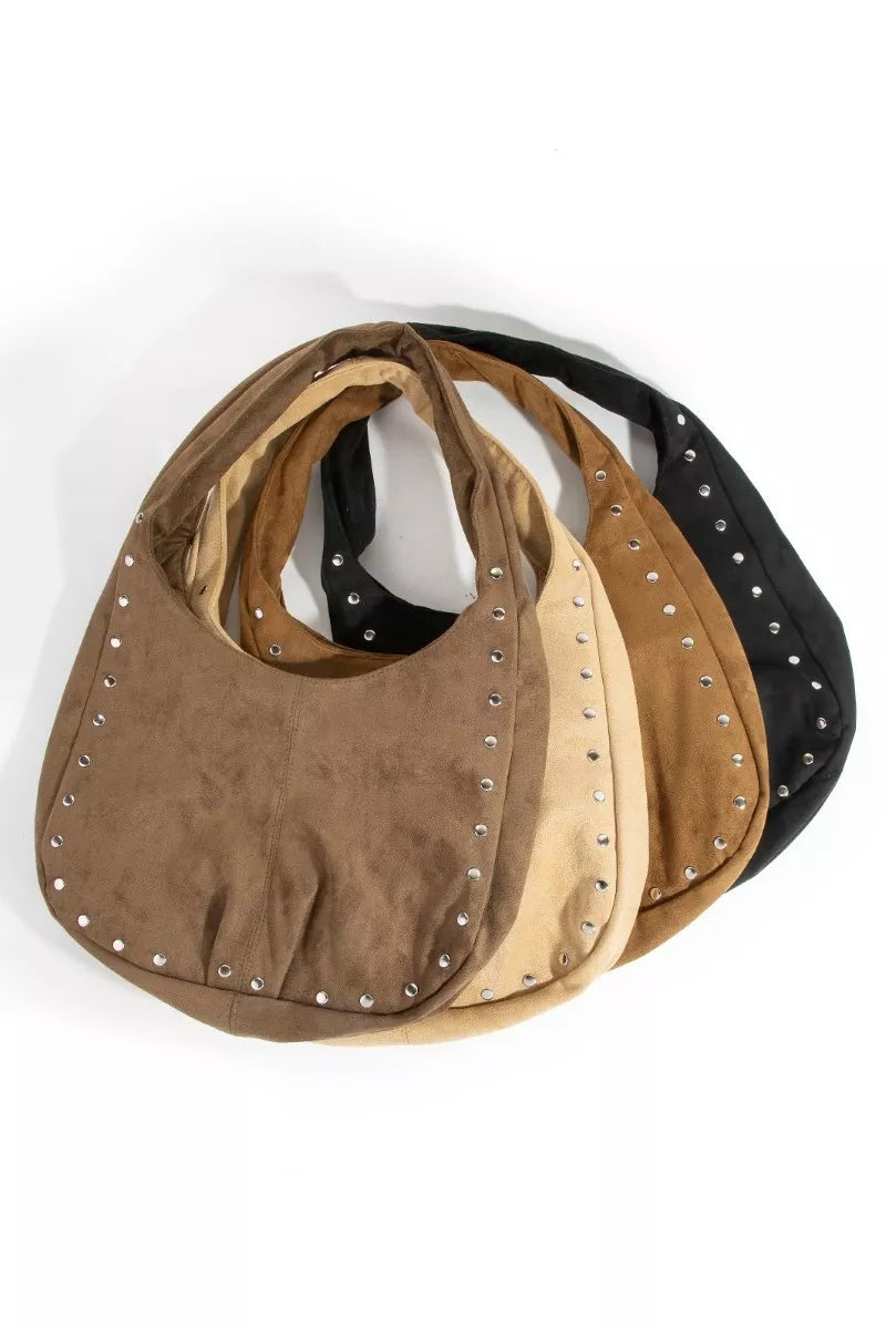 Three suede handbags with studded details in brown, beige, and black on a white background.