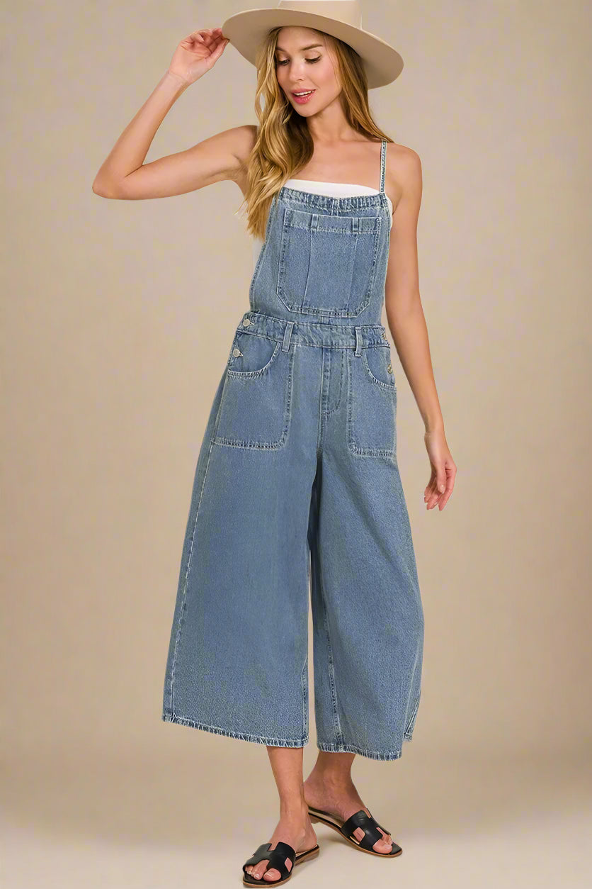 Woman wearing a denim jumpsuit and beige hat on a beige background