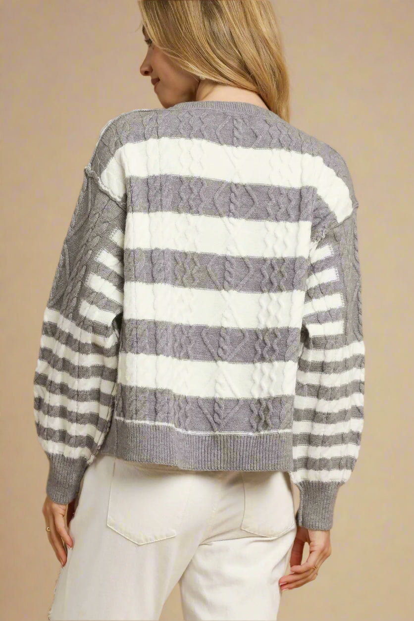 Woman wearing a gray and white striped sweater on a beige background
