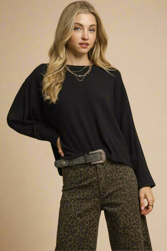 Woman wearing a black top and leopard print pants against a beige background