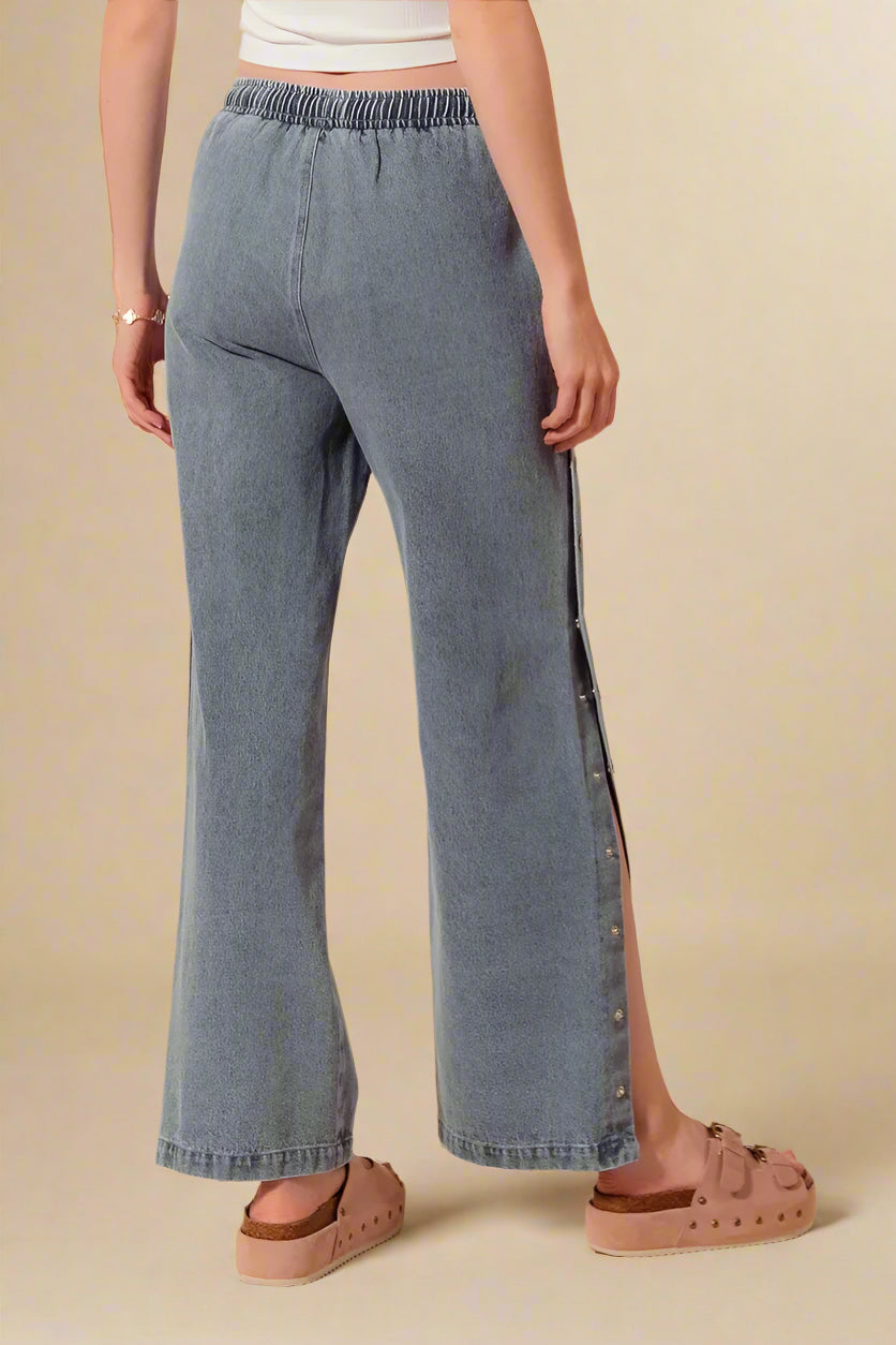 Person wearing blue denim pants with a beige background