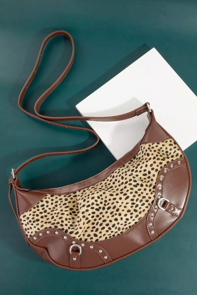 Brown handbag with leopard print section on a teal surface