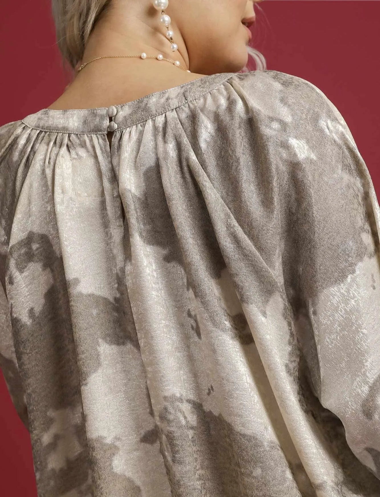 Close-up of a person wearing a plus-size blouse with a camouflage pattern on a red background.