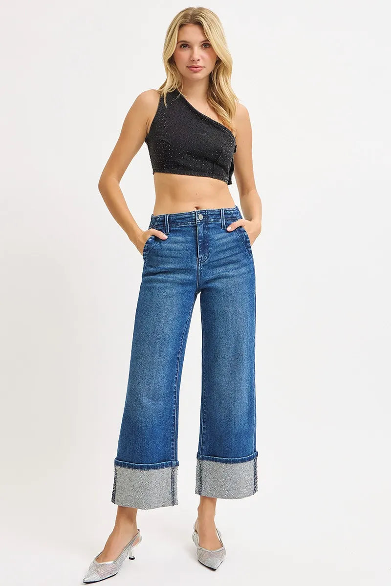 Woman wearing blue wide-leg jeans and a black crop top on a white background