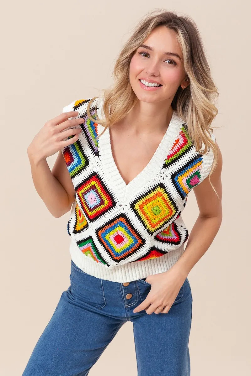 Woman wearing a colorful crochet vest against a beige background