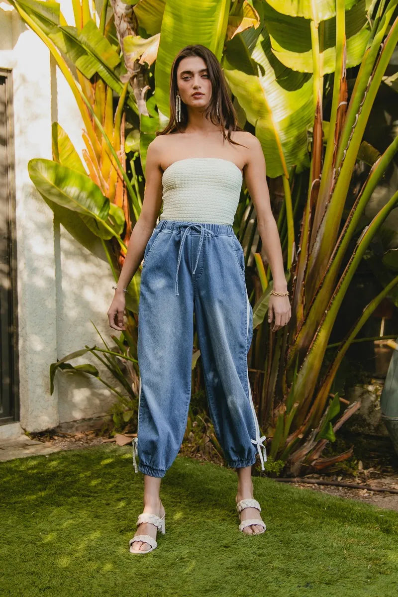 Woman standing in a garden with large green leaves and plants.