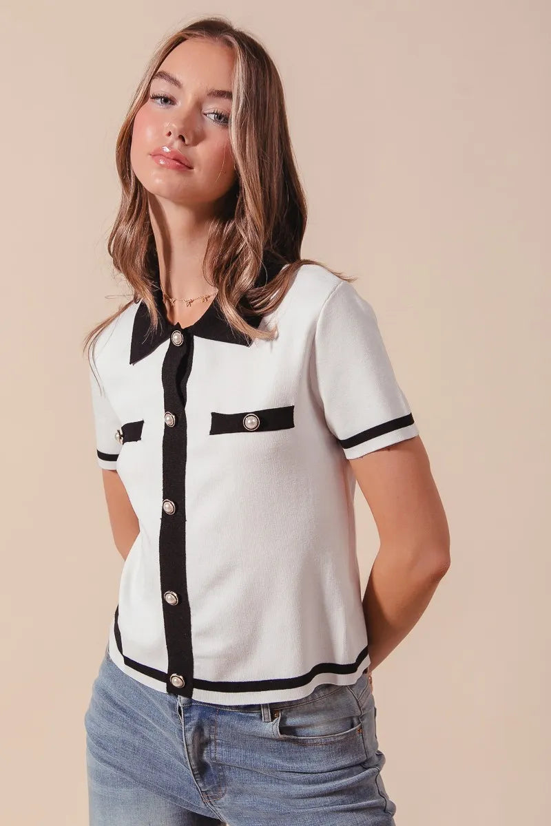 Woman wearing a white and black patterned shirt with blue jeans on a beige background