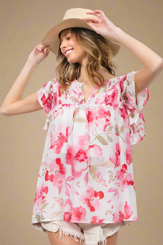 Woman wearing a floral blouse and straw hat against a white background