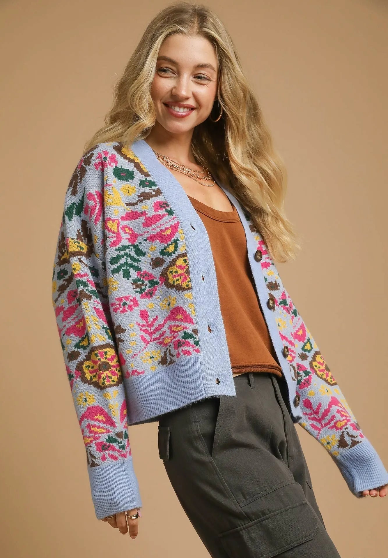 Woman wearing a colorful floral cardigan on a beige background