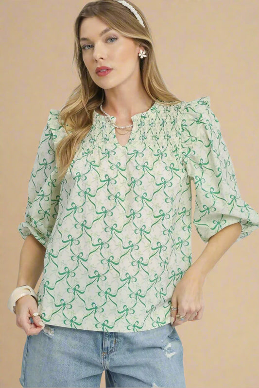 Woman wearing a green patterned blouse with blue jeans on a beige background