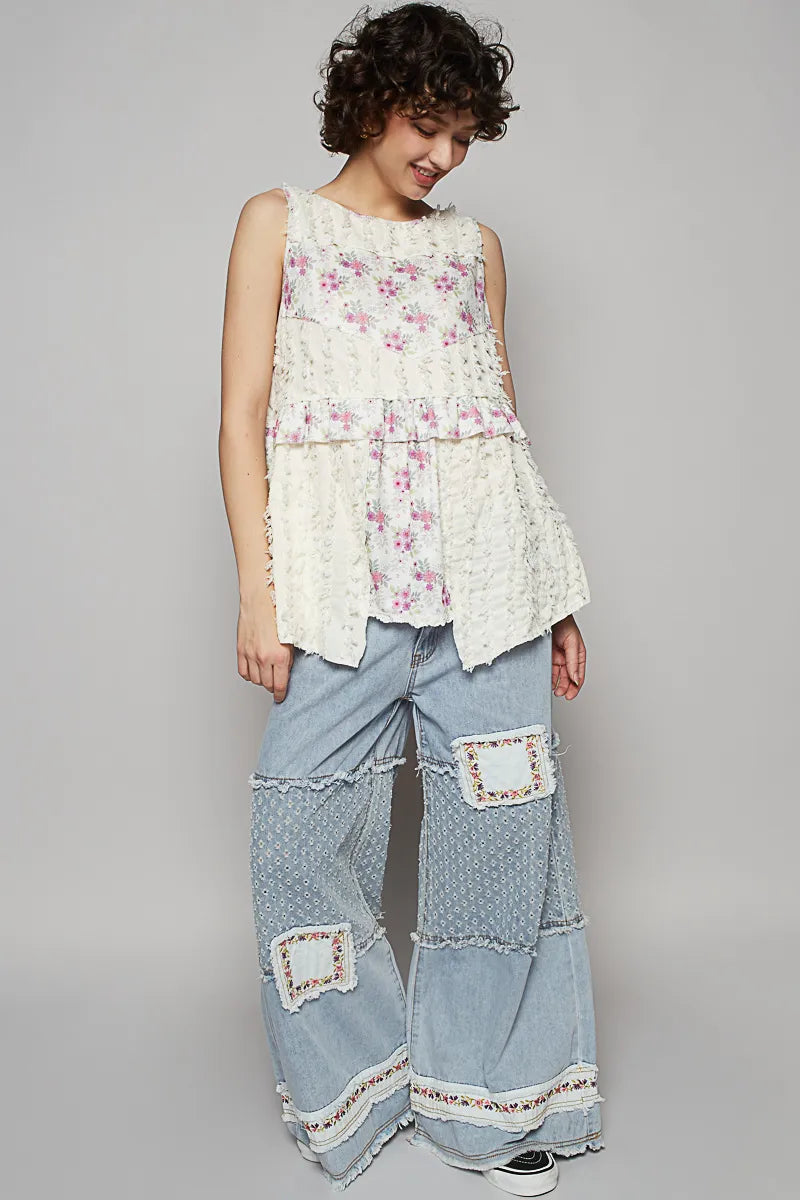 Woman wearing a floral top and patchwork pants on a gray background