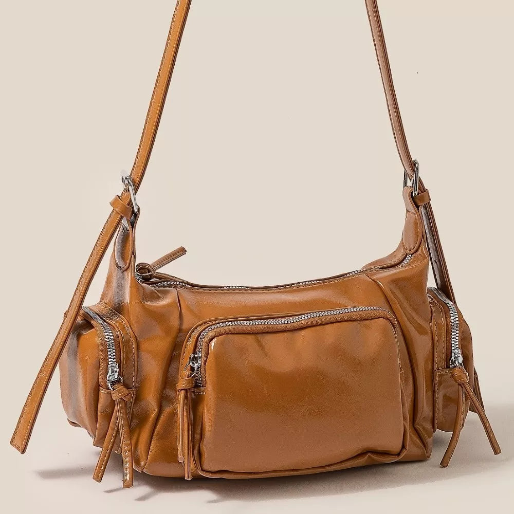 Brown leather handbag with multiple pockets on a beige background