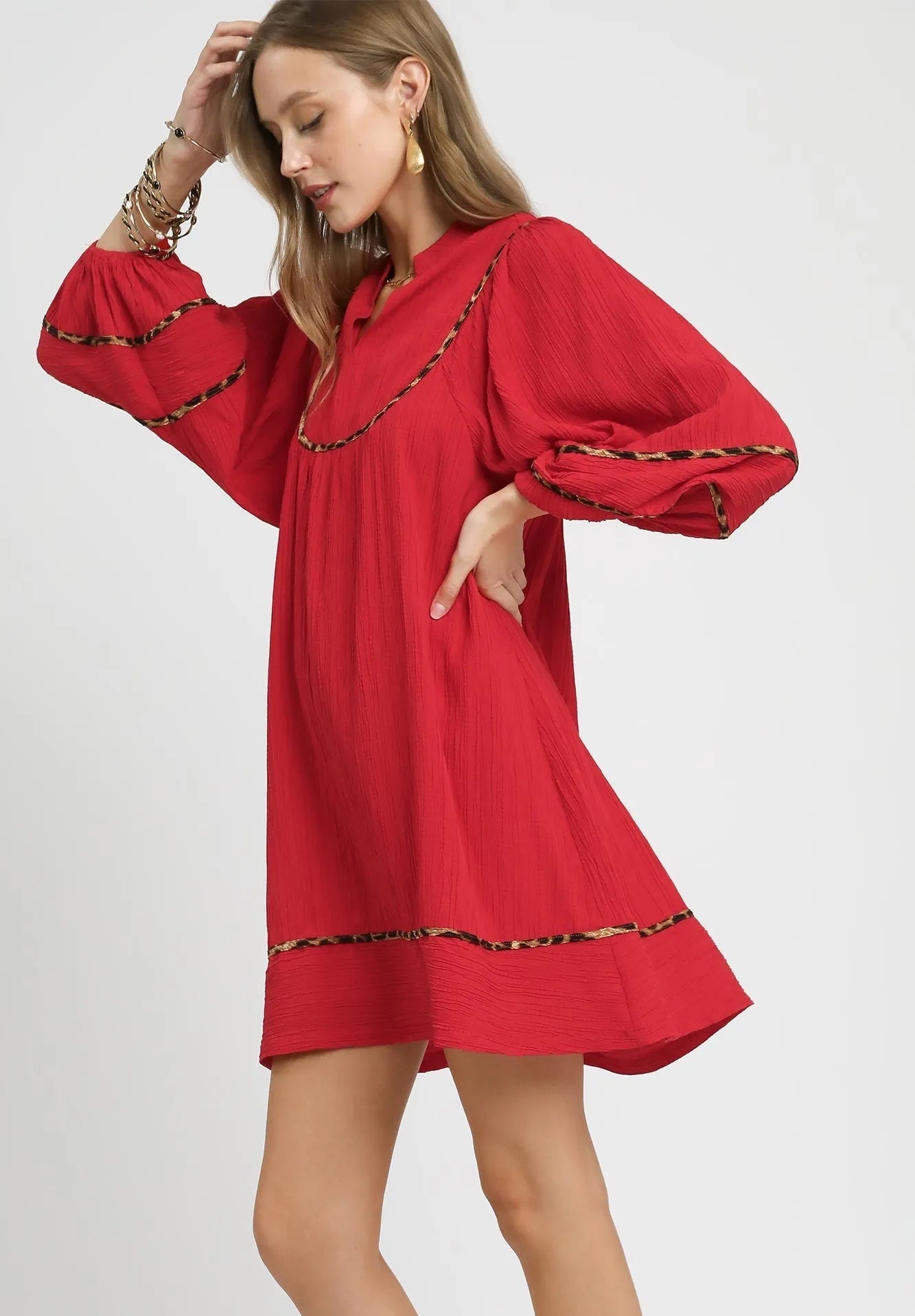 Red dress with long sleeves and decorative trim on a white background
