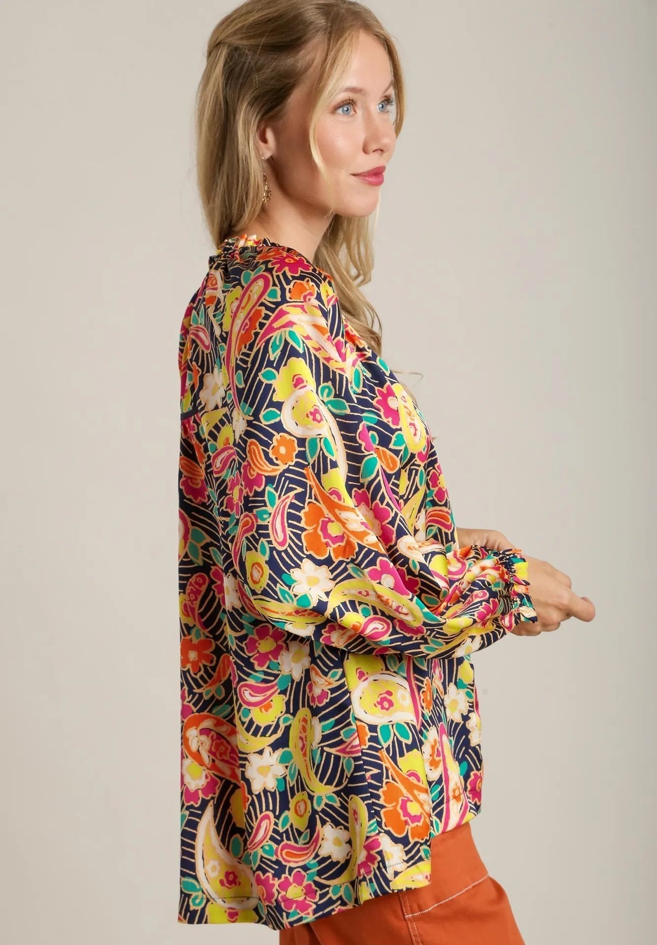Woman wearing a colorful floral blouse against a plain background