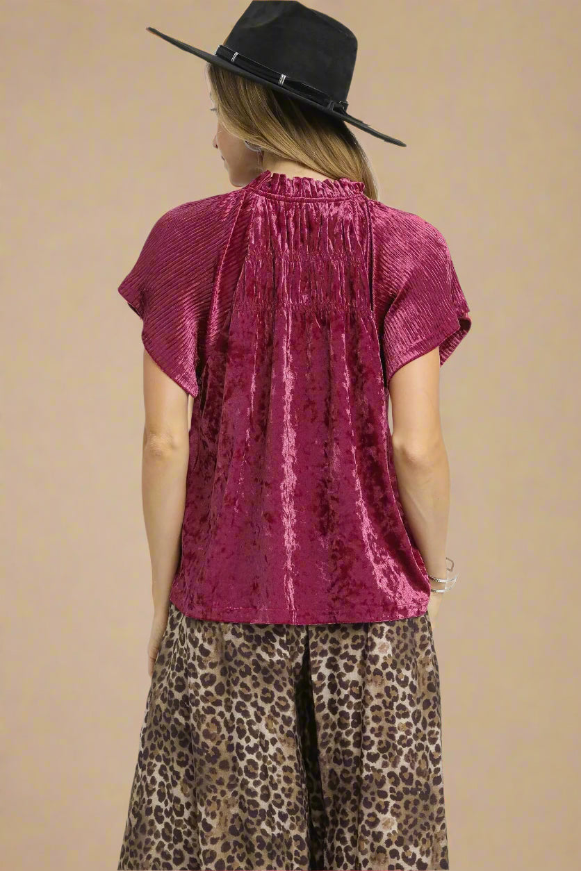 Person wearing a berry-colored top and leopard print pants on a white background