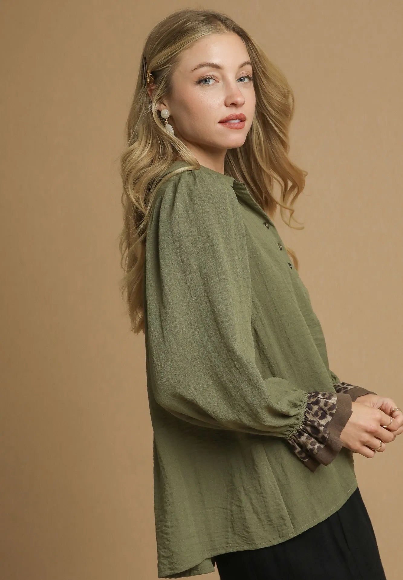 Woman wearing an olive green blouse with a brown background