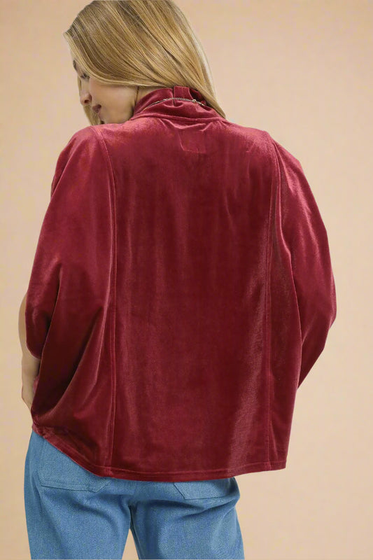 Person wearing a red velvet top on a beige background