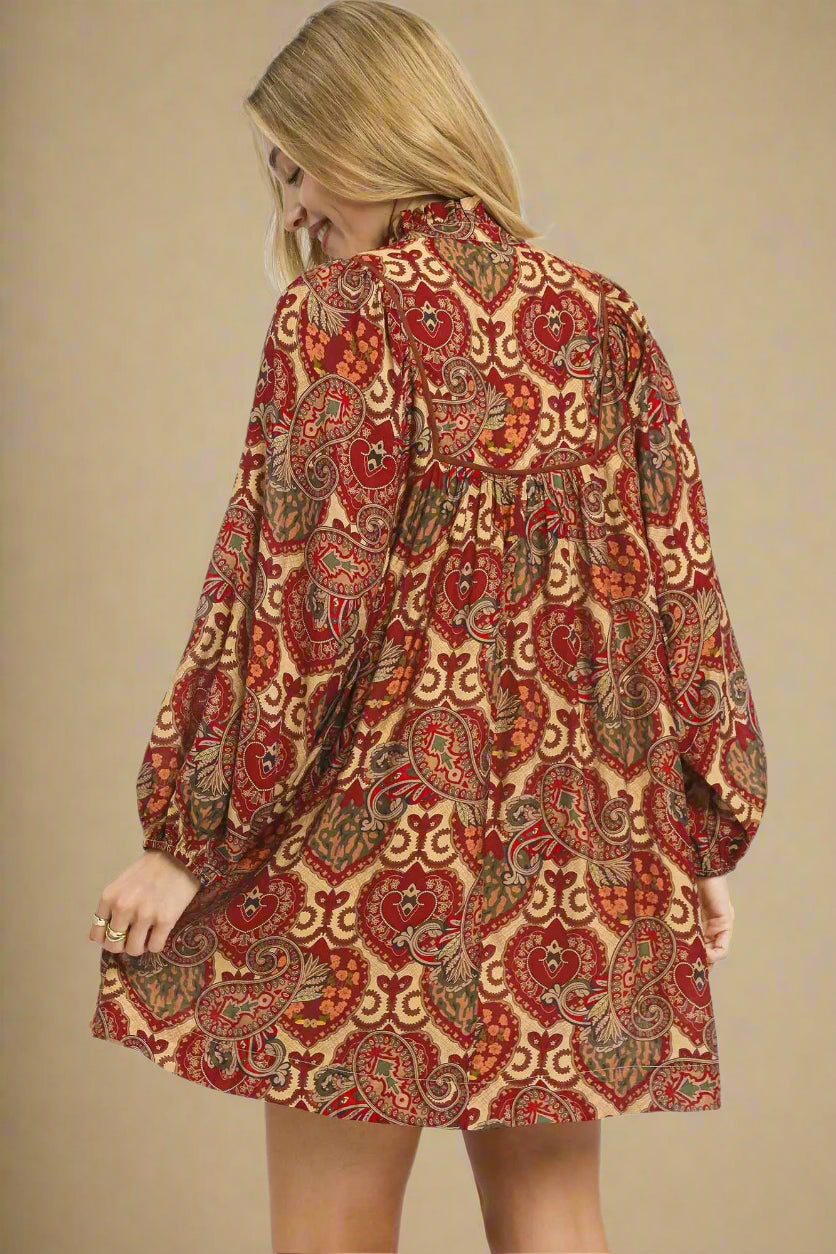 Woman wearing a red and gold patterned dress on a beige background