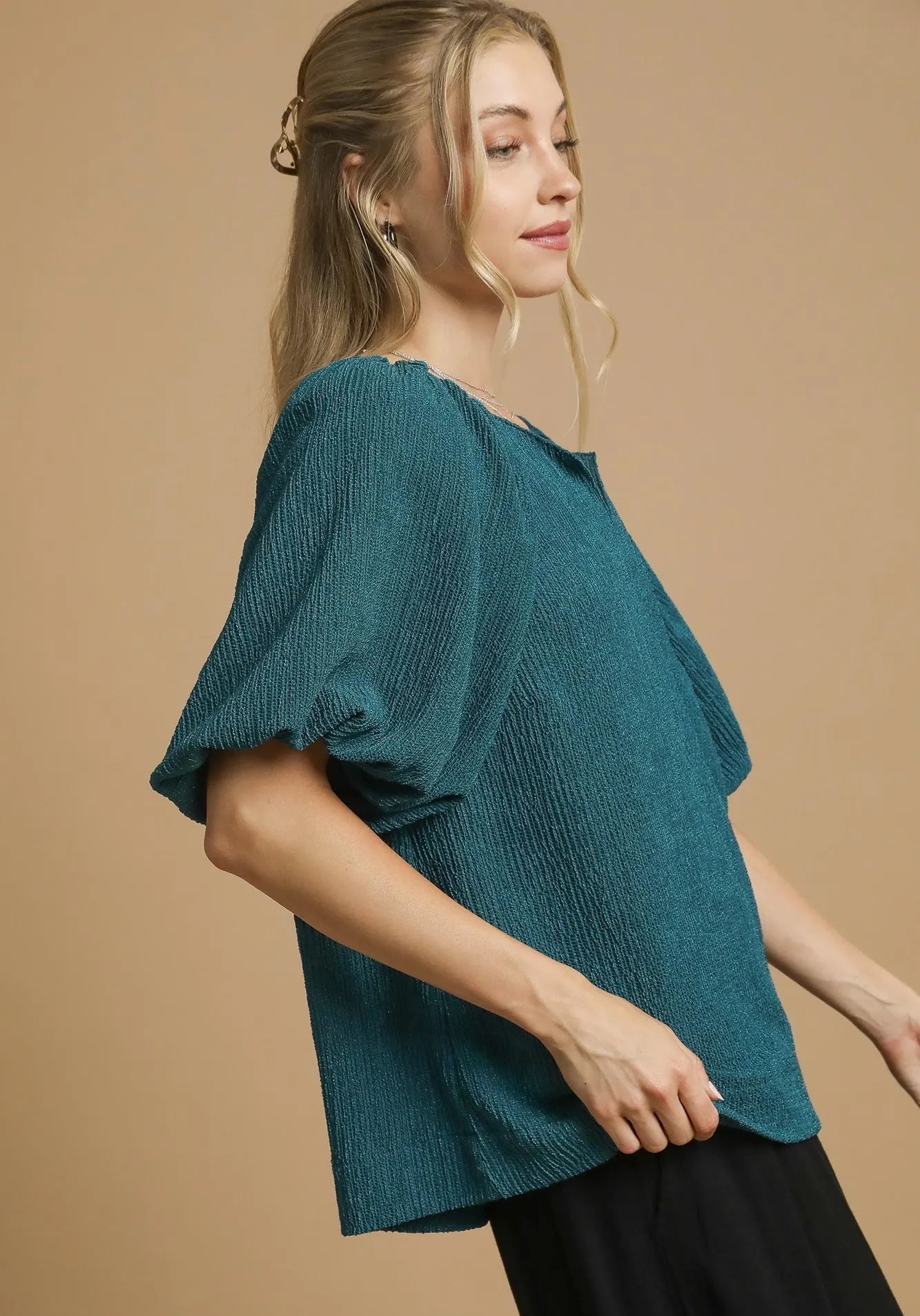 Woman wearing a teal top against a beige background